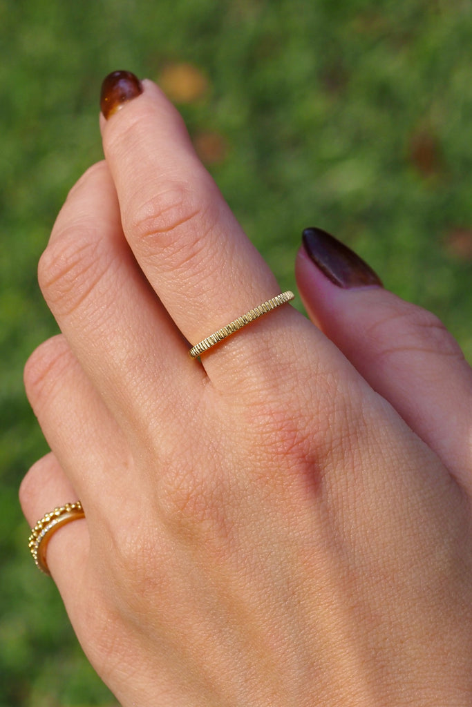 ジュエリースタジオMASHIROのアップサイクルジュエリー。イエローゴールドの木目デザインリングの着用画像。