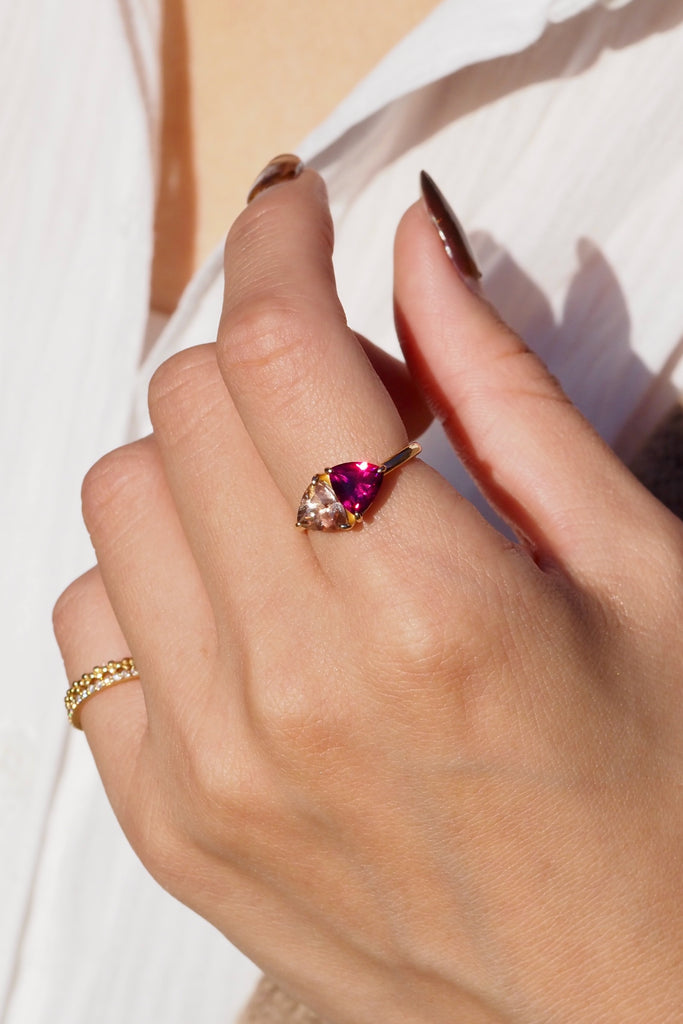 ジュエリースタジオMASHIROのアップサイクルジュエリー。オレゴンサンストーン・トリリアントカット・約1.07ct・約6.8*6.6mm・アメリカオレゴン州産｜ロードライトガーネット・トリリアント・約1.17ct・約7mm・インド産。シャンパンゴールドカラーのコンビリングの着用画像。