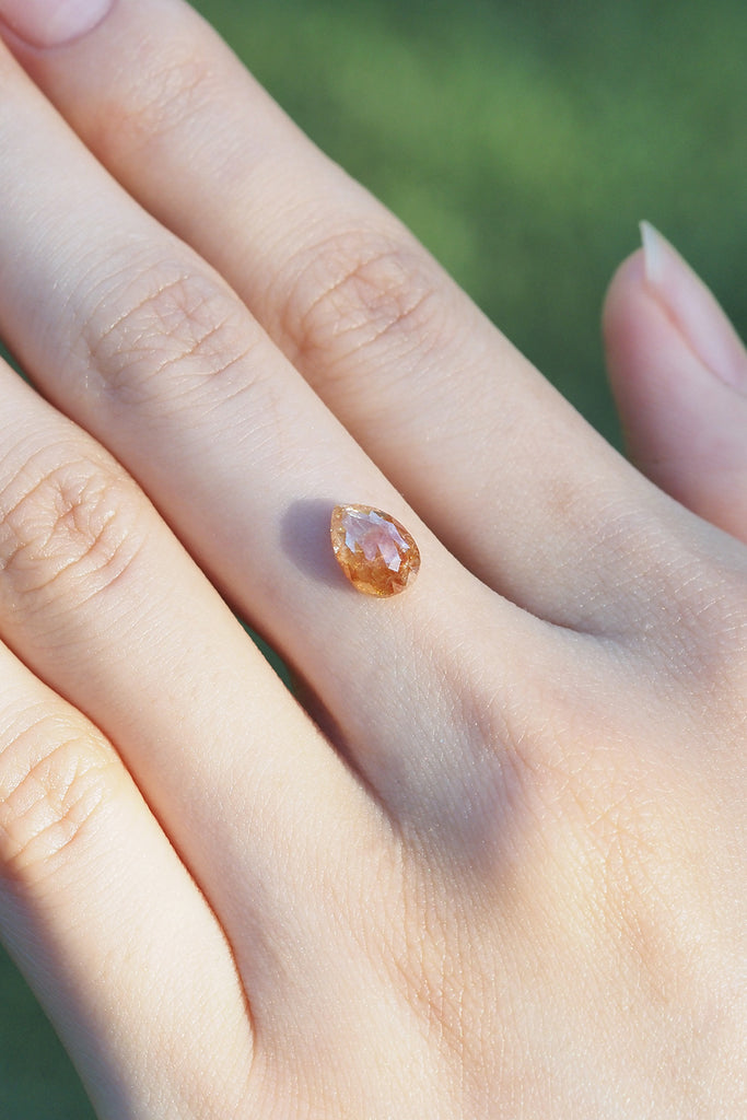 MASHIROナチュラルカラーダイヤモンド・レッドファントムスカイ・サンセットドロップの1石を指の上に乗せた写真