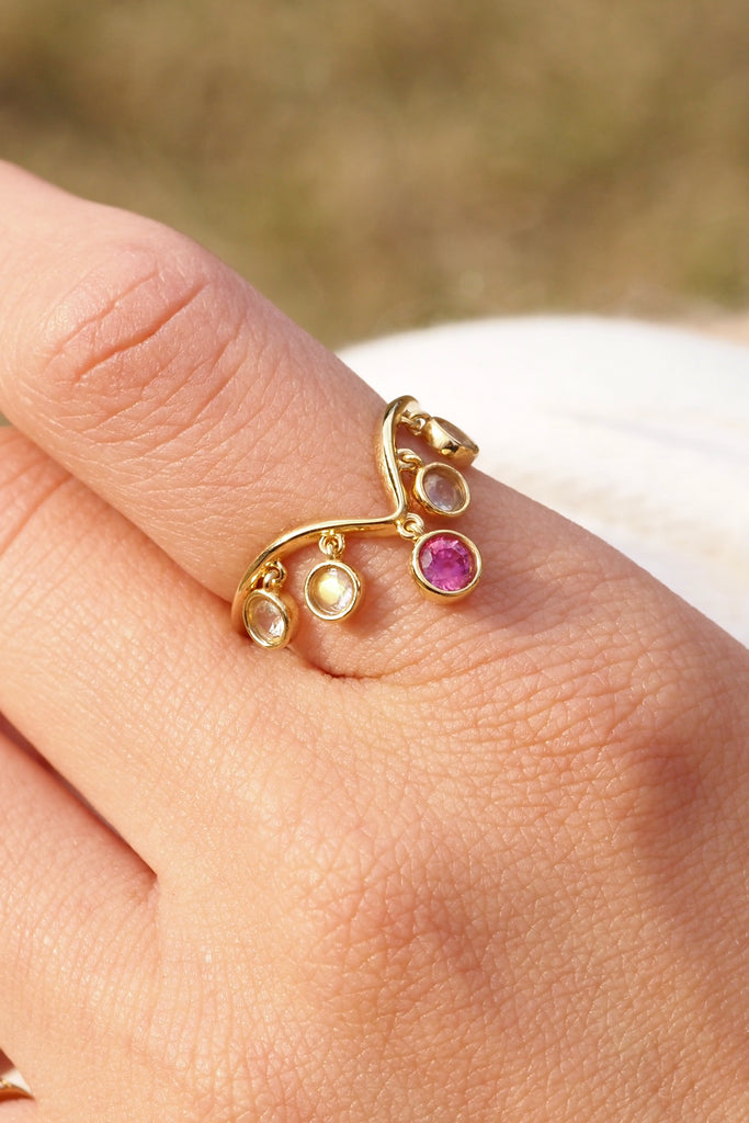 ジュエリースタジオMASHIROのアップサイクルジュエリー。レインボームーンストーン（４石）・ラウンド・合計：約0.36ct・約3mm｜ピンクサファイア・ラウンド・約0.29ct・約3.8mm。シャンパンゴールドカラーのシャンデリアリングの着用画像。